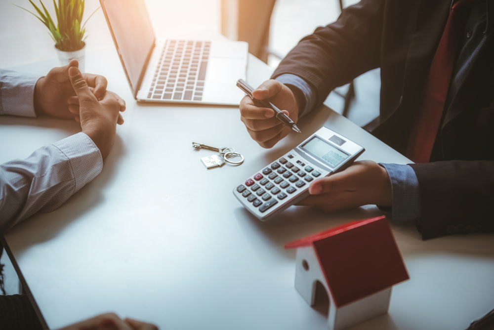 Real estate agent showing a client numbers of a calculator.